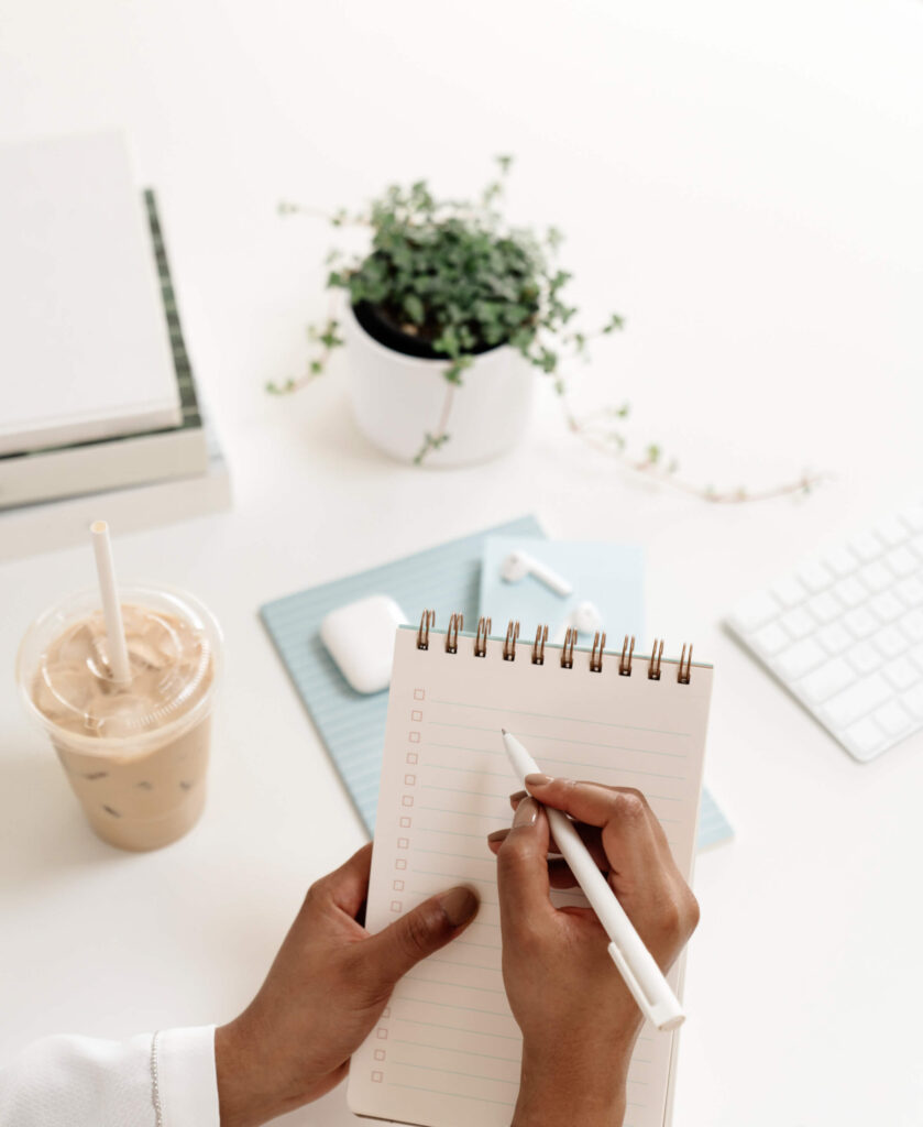 A person holding a notepad and pen getting ready to write a to-do list.