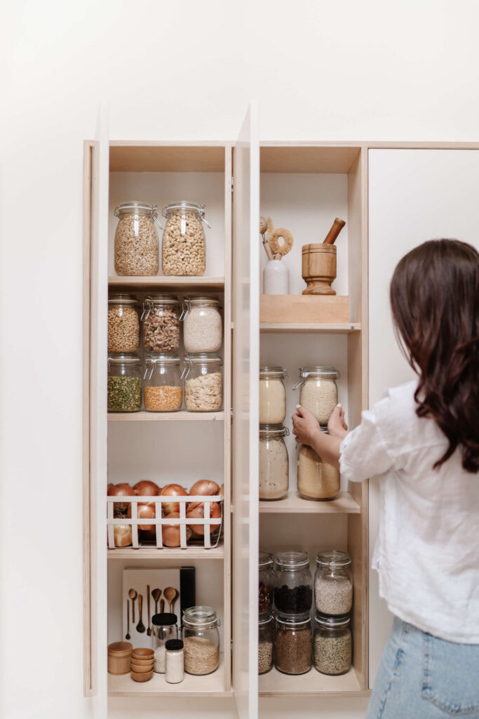 Woman putting a jar back inside her pantry.