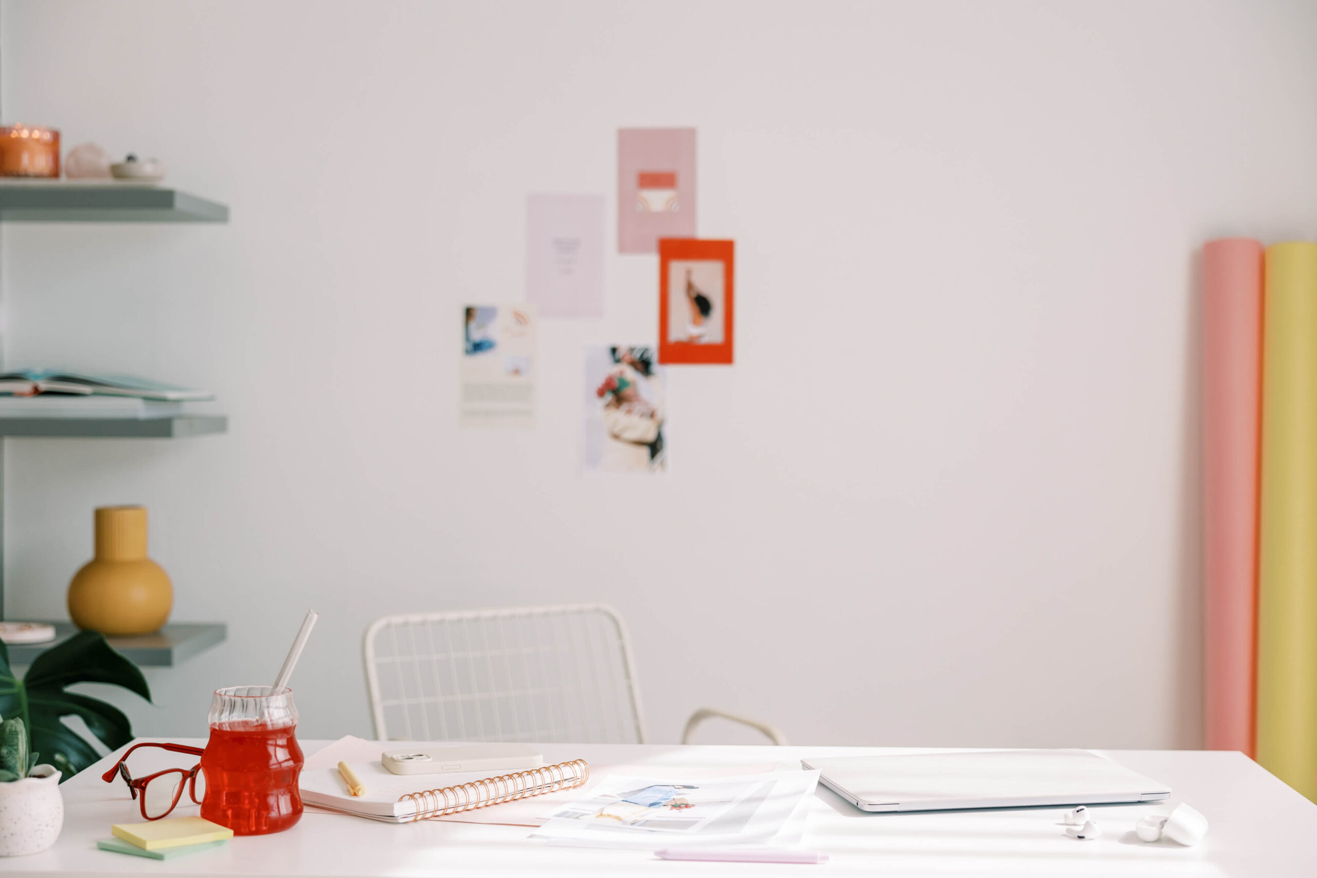 office space with photos on the wall, desk with a closed laptop, and pops of bright colors throughout the space.